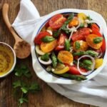 bowl of asparagus tomato salad with olive oil on the side