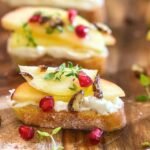 Two toasts topped with whipped goat cheese, apples and honey drizzled on top.