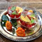 2 glasses of a wine spritzer recipe with peaches and raspberries